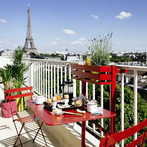 Red Metal Table, Chairs, and a Railing Shelf for Pot in balcony